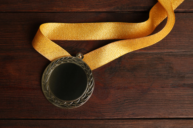 Photo of Gold medal on wooden background, top view. Space for design