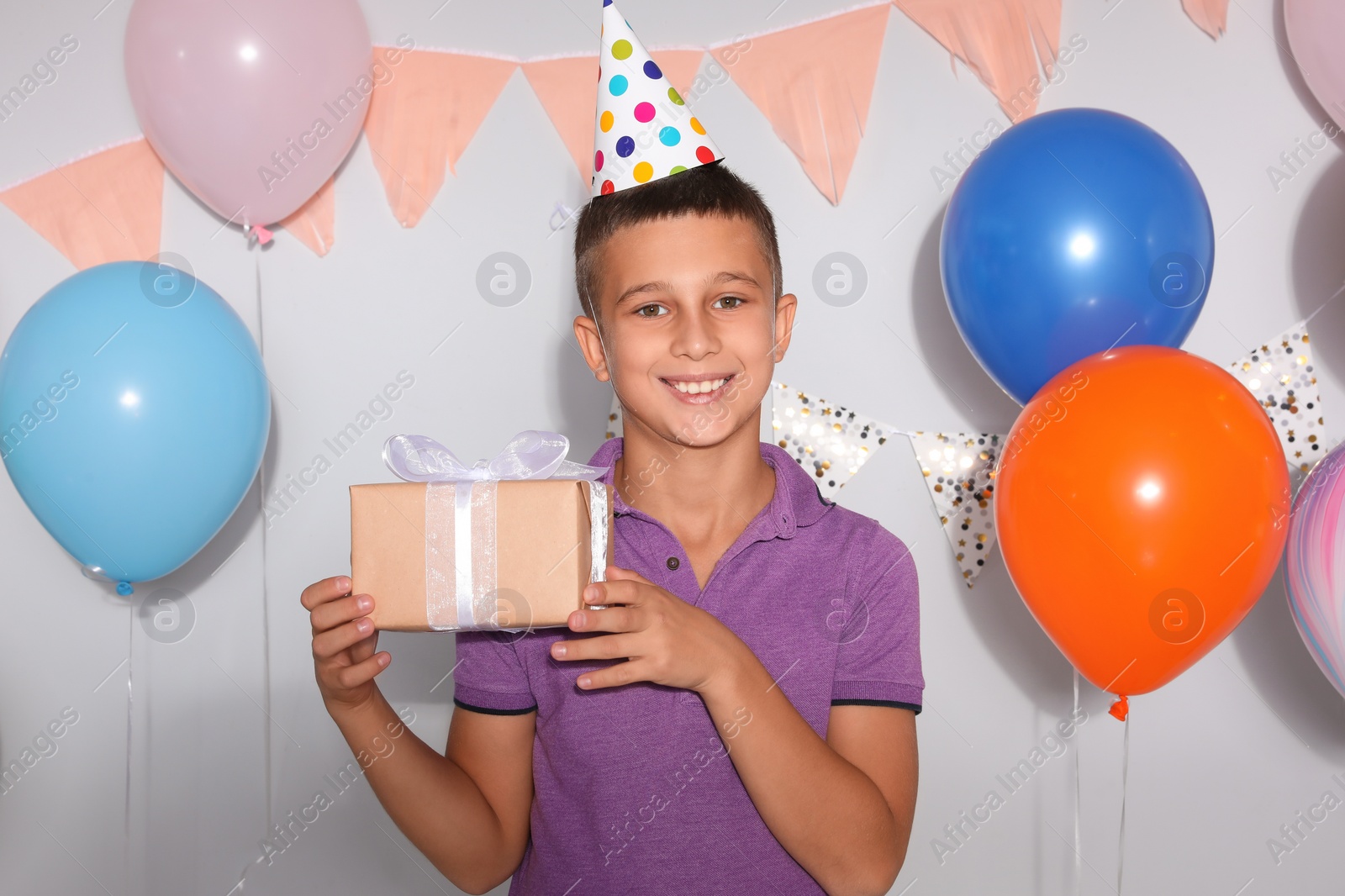 Photo of Happy boy with gift box at birthday party indoors