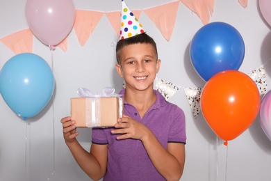 Photo of Happy boy with gift box at birthday party indoors