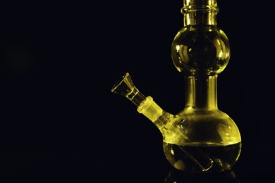 Glass bong on black background, space for text. Smoking device