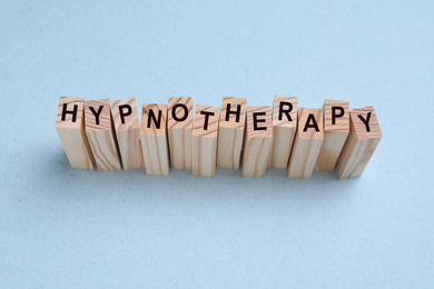 Photo of Wooden blocks with word HYPNOTHERAPY on white background, above view