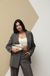 Photo of Beautiful woman with bag in formal suit on color background. Business attire
