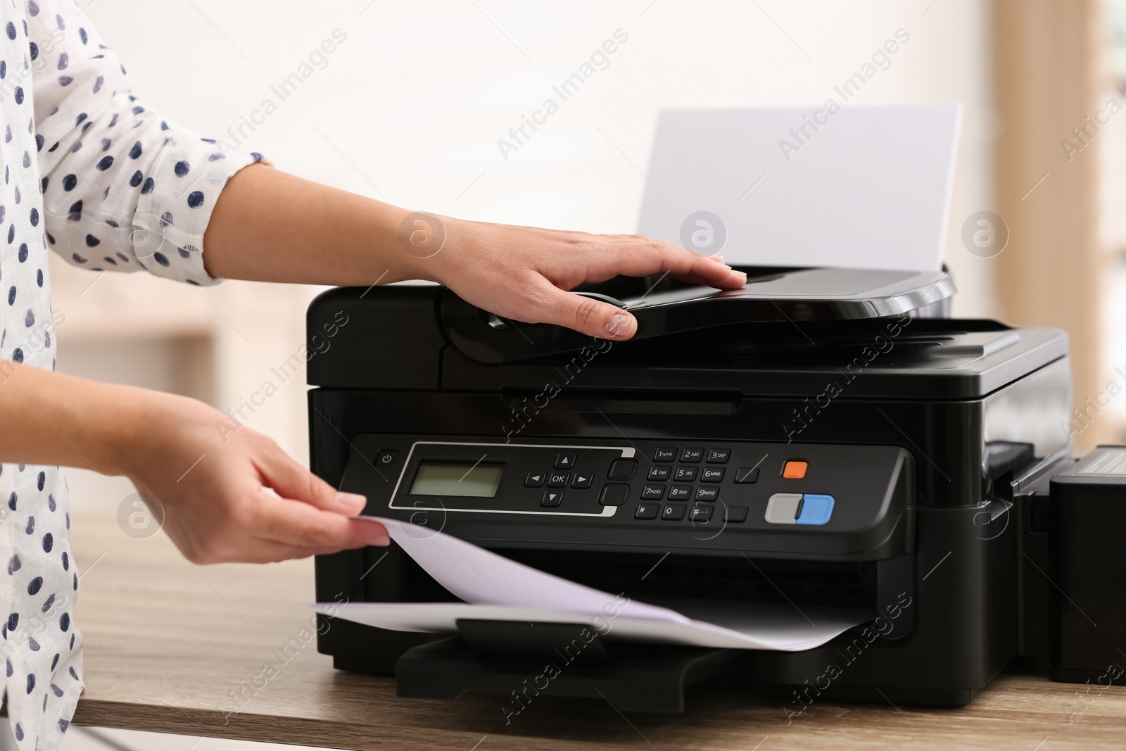 Photo of Employee using modern printer in office, closeup