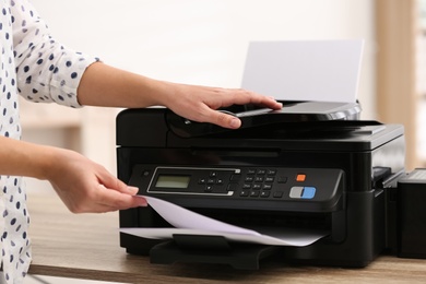 Photo of Employee using modern printer in office, closeup