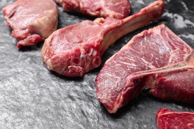 Photo of Fresh raw beef cuts on grey textured table, closeup