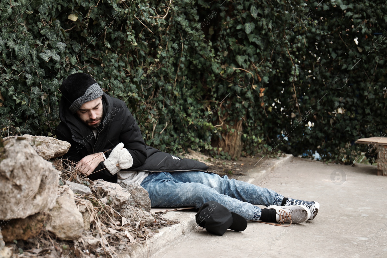 Photo of Poor homeless man lying on street in city