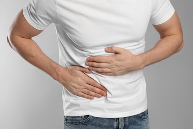 Photo of Man suffering from pain in lower right abdomen on light grey background, closeup. Acute appendicitis