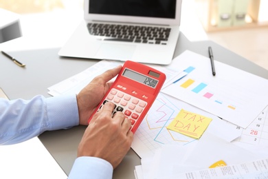 Photo of Tax accountant working with calculator at table