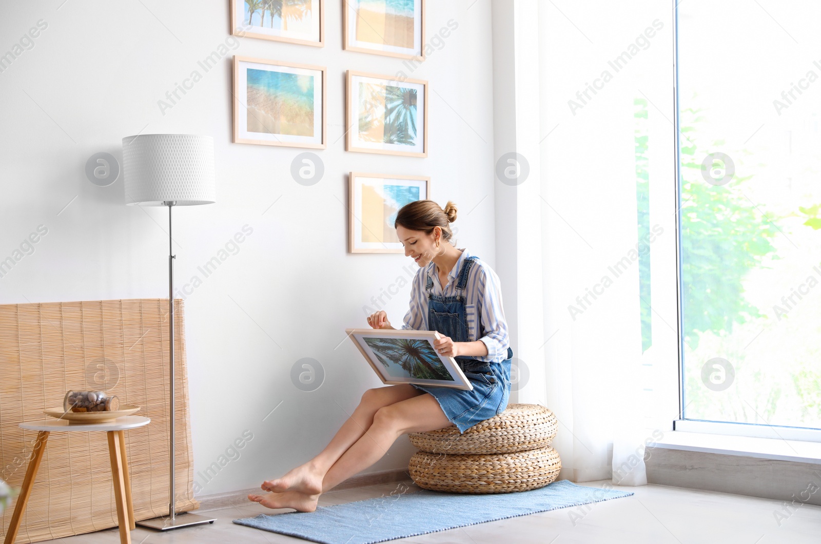 Photo of Female interior designer decorating white wall with pictures indoors