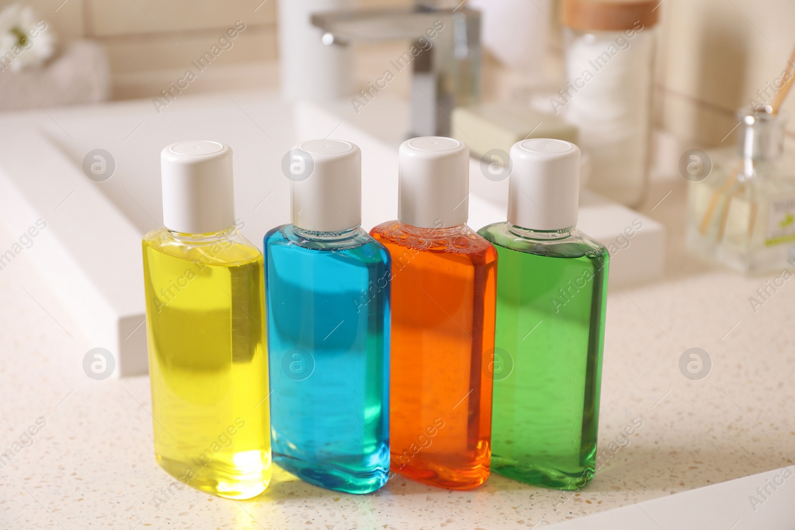 Photo of Fresh mouthwashes in bottles on countertop near sink, closeup