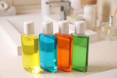 Photo of Fresh mouthwashes in bottles on countertop near sink, closeup