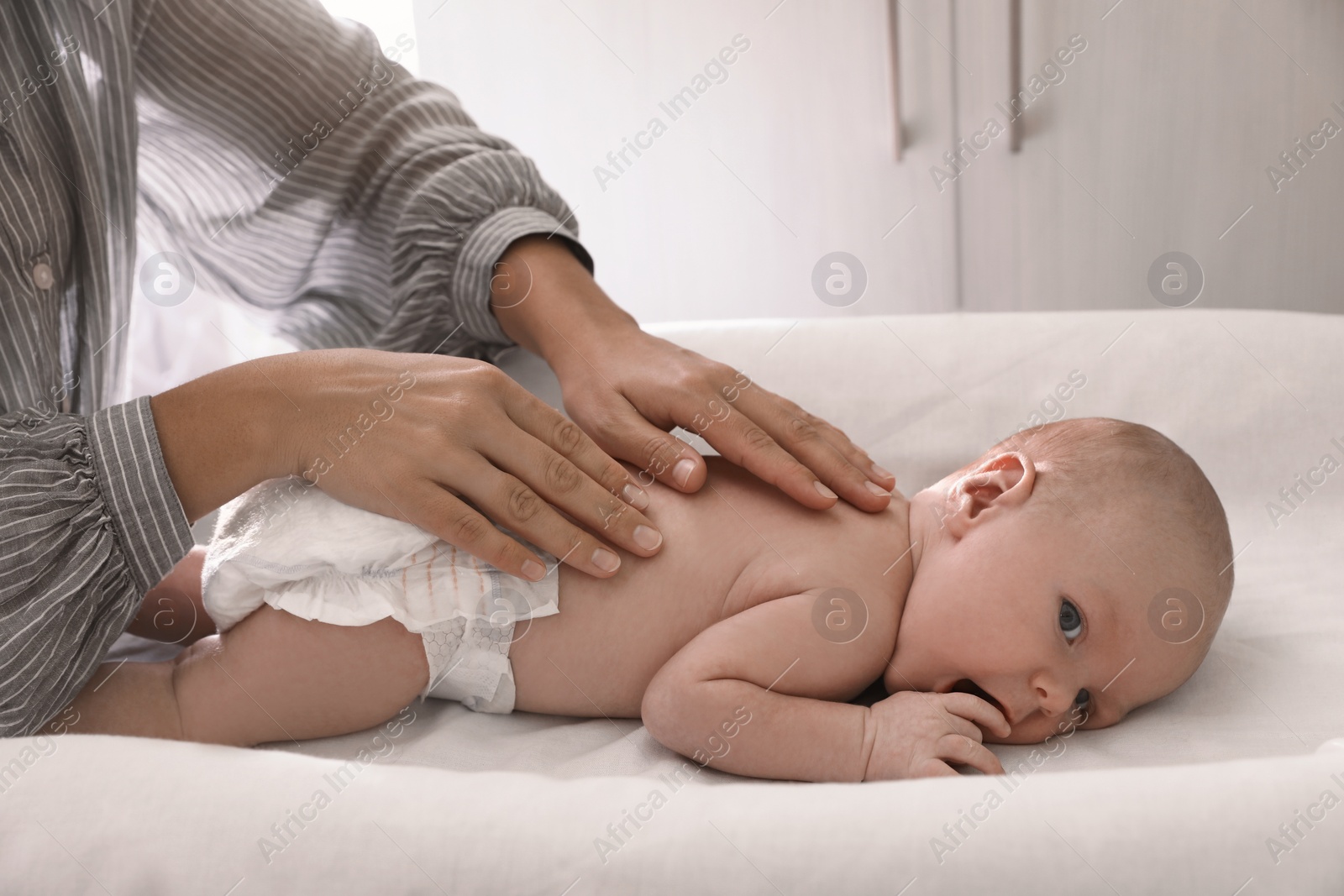 Photo of Mother massaging her little baby on changing table indoors, closeup