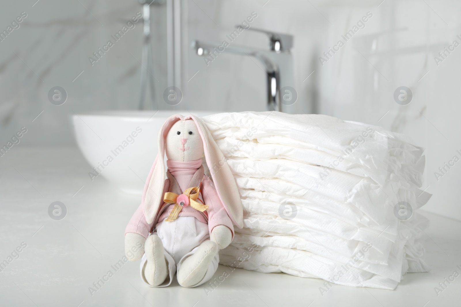 Photo of Stack of baby diapers and toy bunny on counter in bathroom