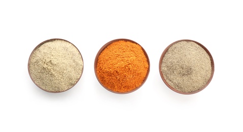 Bowls with different kinds of milled pepper on white background, top view