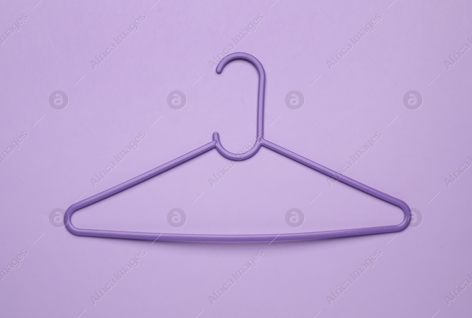 Photo of Empty clothes hanger on violet background, top view