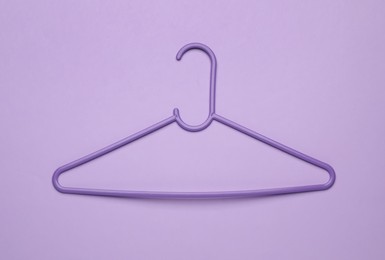Photo of Empty clothes hanger on violet background, top view