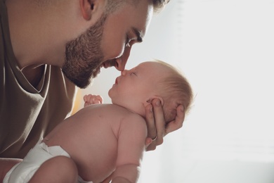 Photo of Father with his newborn son on light background, closeup