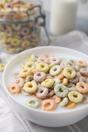 Tasty colorful cereal rings and milk in bowl on table, closeup