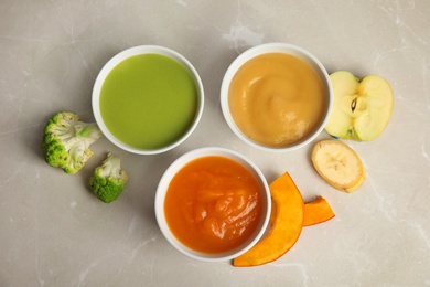 Photo of Bowls with different baby food on gray background, flat lay