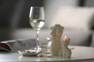 Photo of Beautiful body shaped candles and jewelry on white table indoors, space for text