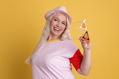 Portrait of mature woman in hipster outfit on color background