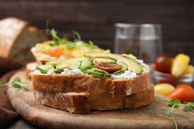 Photo of Tasty vegan sandwich with avocado, tomato and spinach on wooden table, closeup