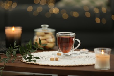 Tea, cookies and decorative elements on wooden table against blurred lights indoors