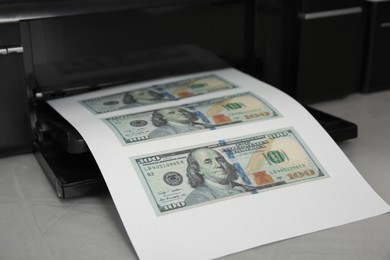 Photo of Printing dollar banknotes on grey table, closeup. Fake money concept