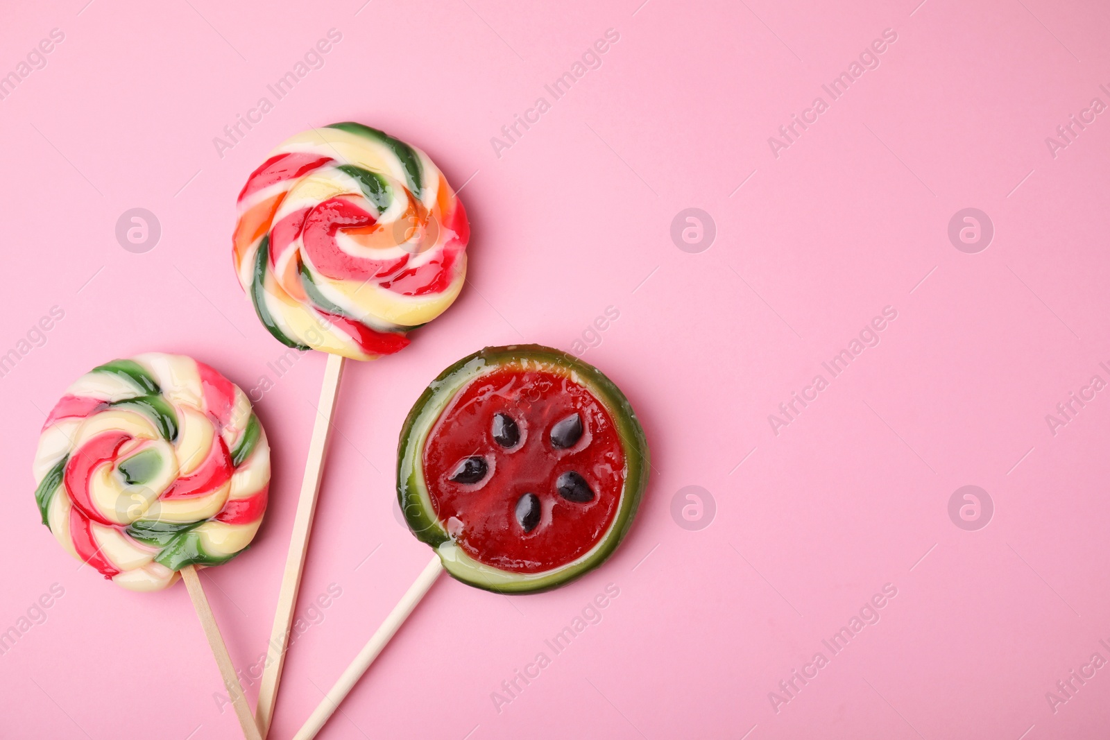 Photo of Different colorful lollipops on pink background, flat lay. Space for text