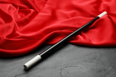 Beautiful magic wand and red fabric on black table