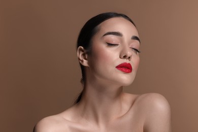 Photo of Portrait of beautiful young woman with red lips on brown background, closeup
