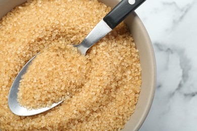 Photo of Brown sugar in bowl and spoon on white marble table, top view