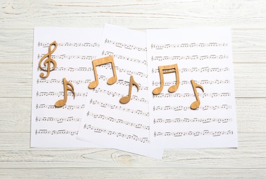 Photo of Sheets and music notes on light wooden background, top view