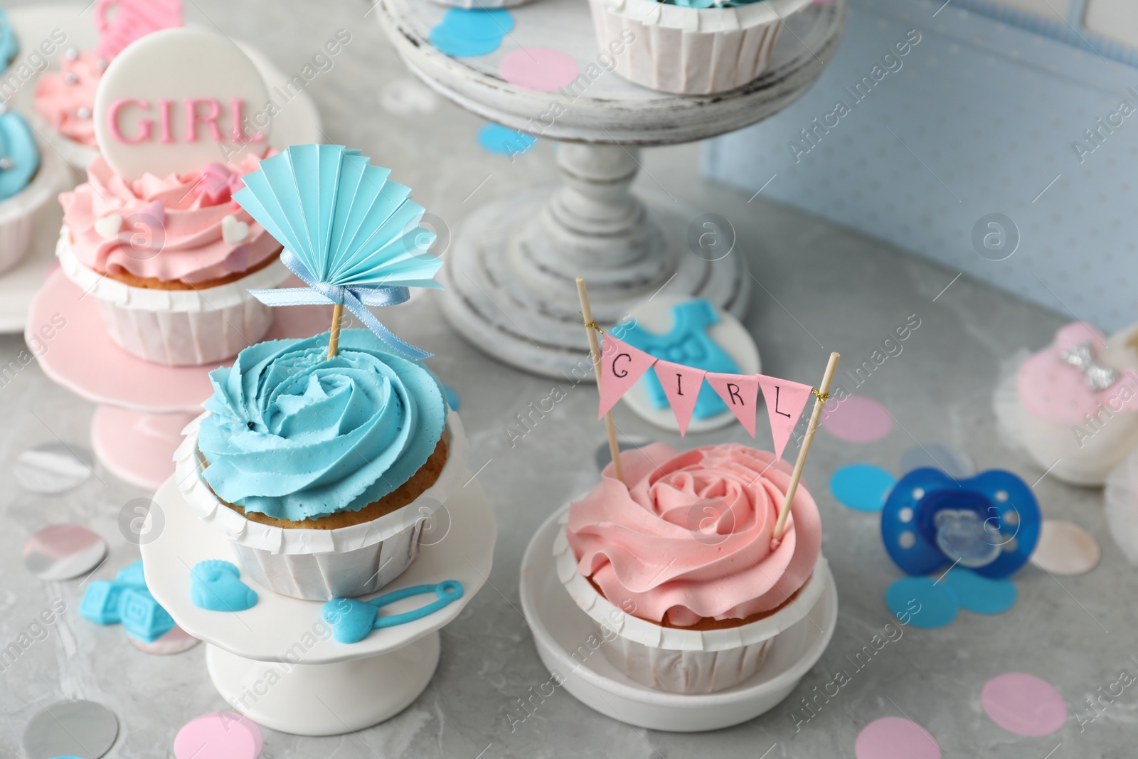 Photo of Delicious cupcakes with light blue and pink cream for baby shower on grey table