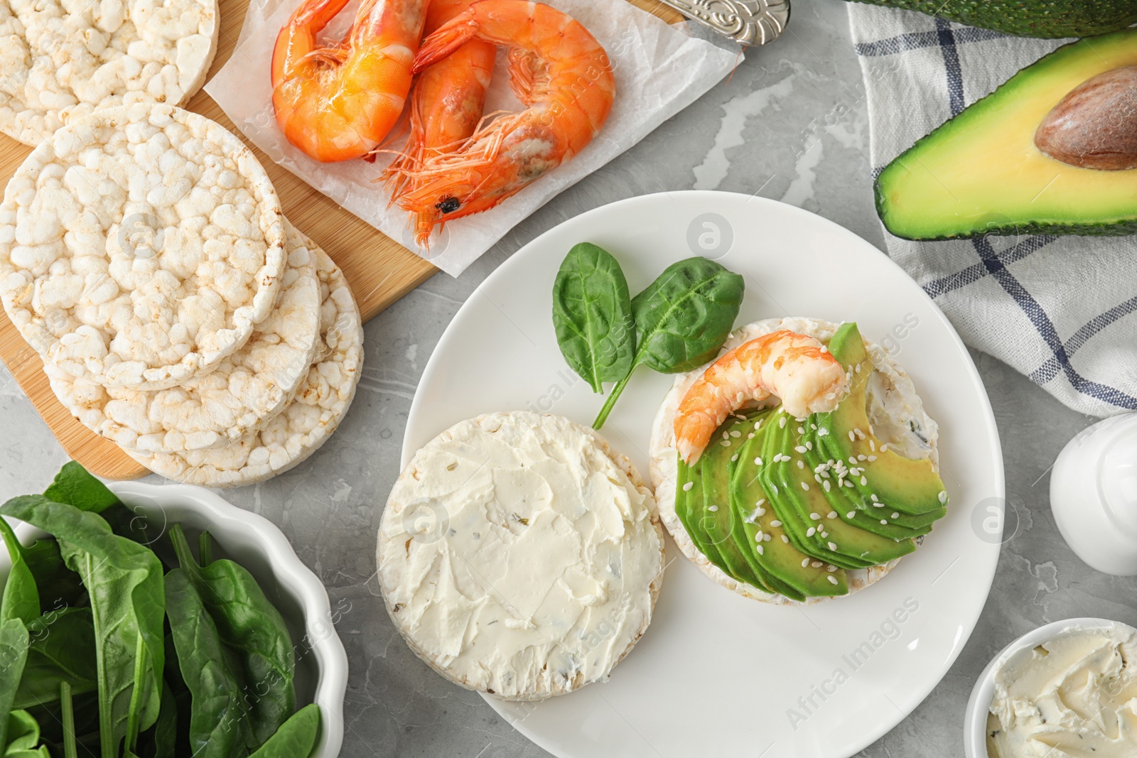 Photo of Puffed rice cake with shrimp and avocado served on grey marble table, flat lay
