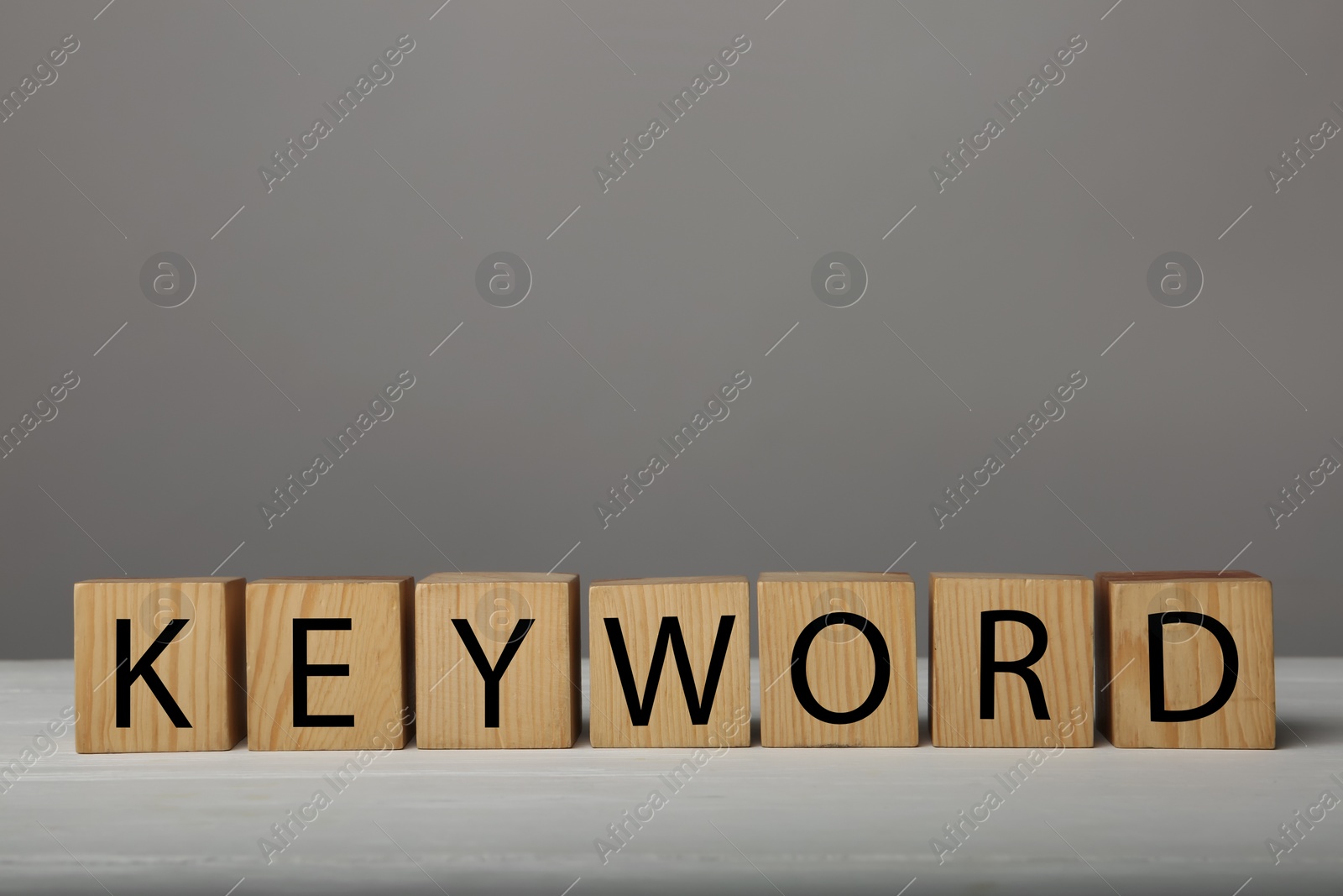 Photo of Word KEYWORD made of wooden cubes on grey background