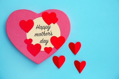 Photo of Surprise for Mother's Day with greeting card and paper hearts on color background