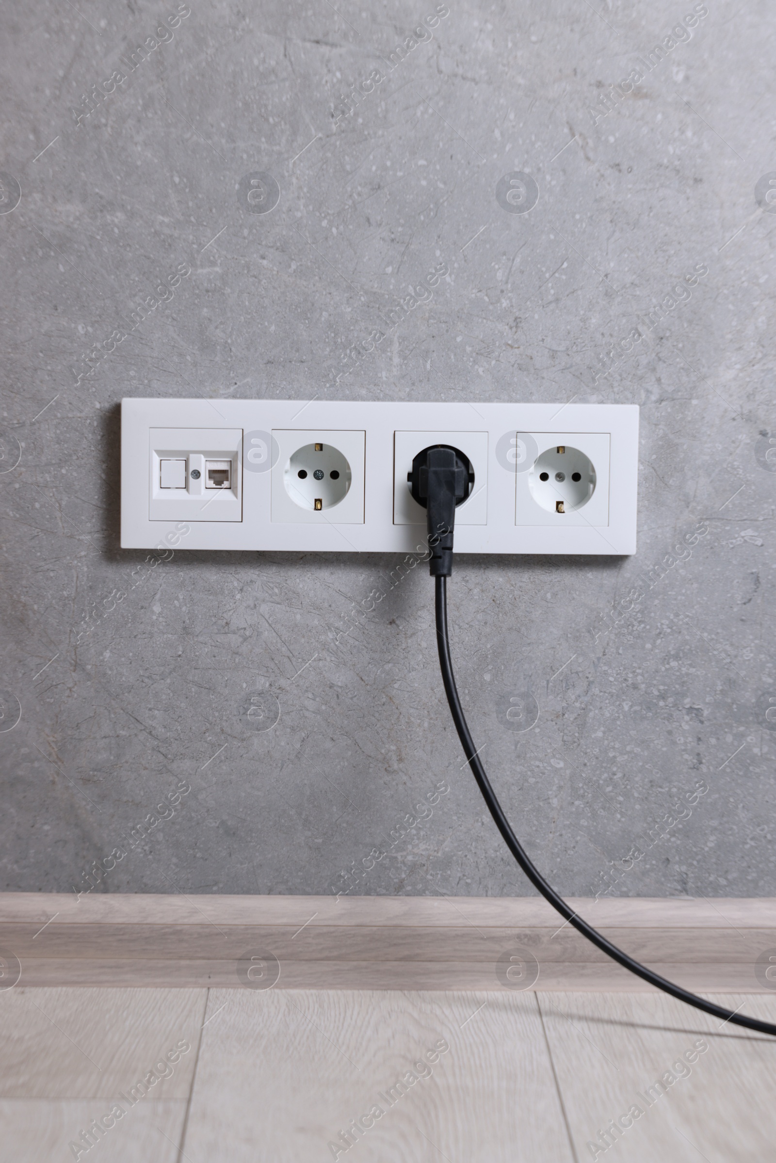 Photo of Power sockets and electric plug on grey wall