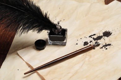 Inkwell with feather, fountain pen and vintage parchments on wooden table