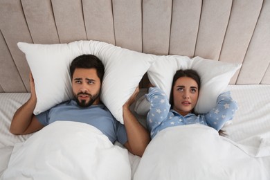 Photo of Young couple suffering from noisy neighbours in bed at home, above view