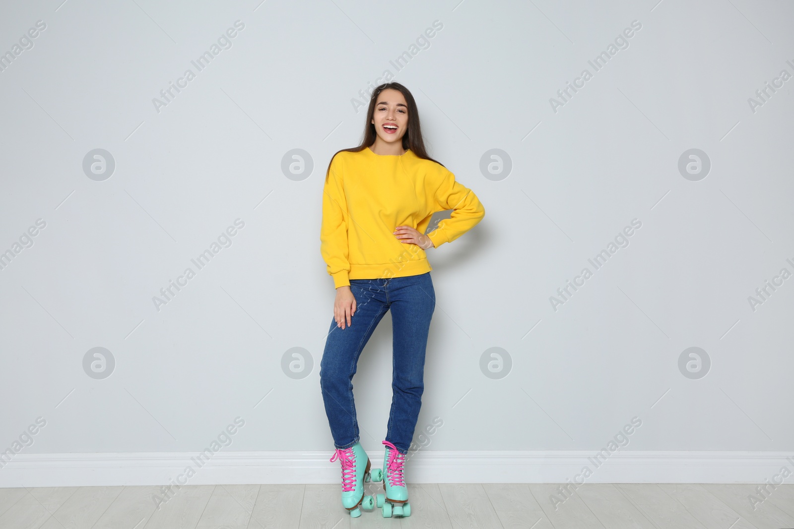 Photo of Full length portrait of young woman with roller skates near color wall