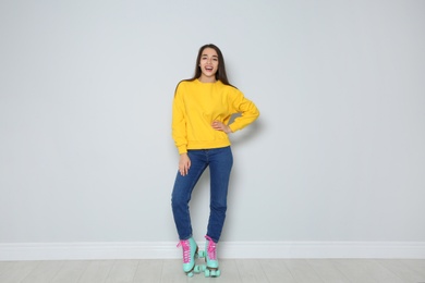 Photo of Full length portrait of young woman with roller skates near color wall