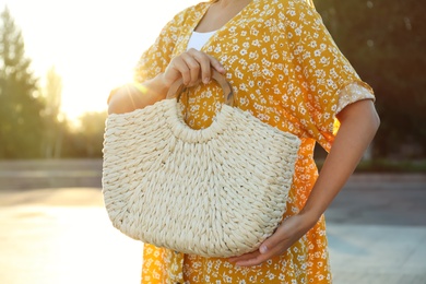 Photo of Young woman with stylish straw bag outdoors, closeup