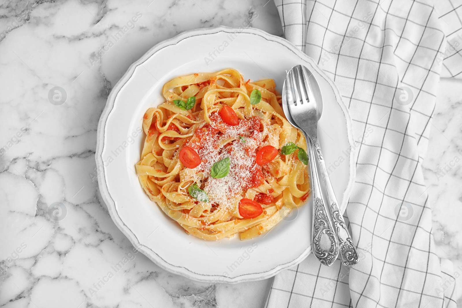 Photo of Tasty pasta and napkin on white marble table, flat lay