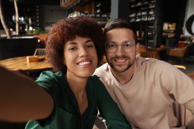 Photo of International dating. Happy couple taking selfie in cafe