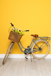 Retro bicycle with wicker basket near color wall