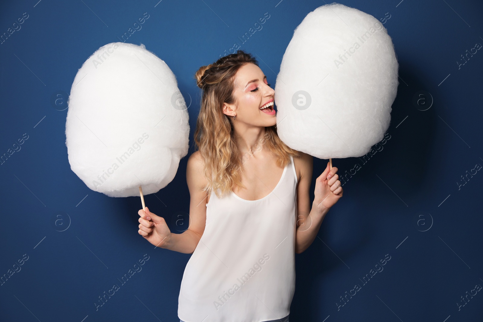 Photo of Portrait of pretty young woman with cotton candy on blue background