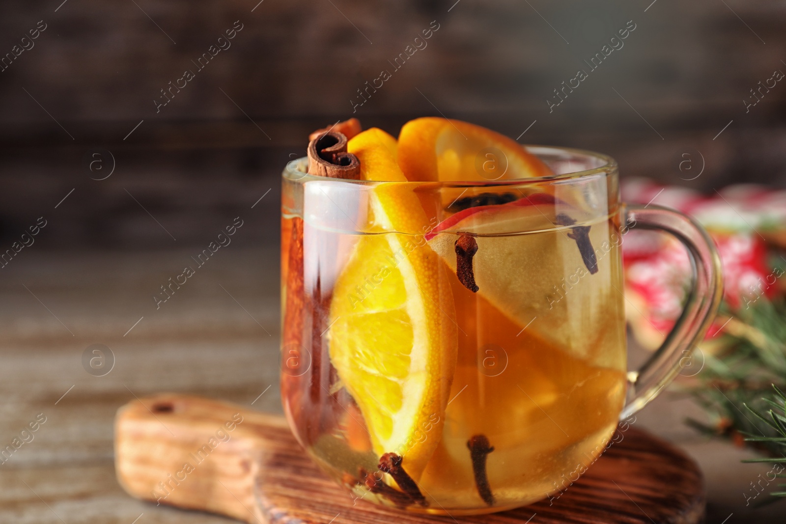 Photo of Aromatic mulled wine on wooden board, closeup