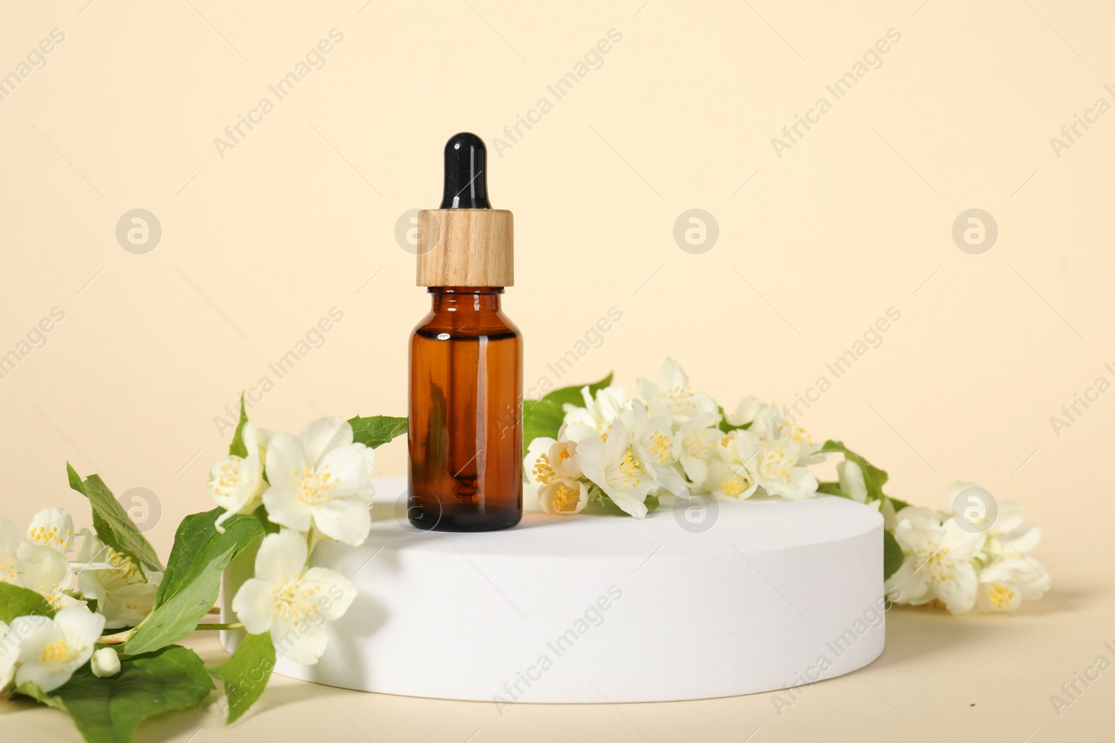 Photo of Presentation of essential oil in bottle and beautiful jasmine flowers against beige background