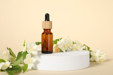 Presentation of essential oil in bottle and beautiful jasmine flowers against beige background